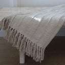 A cream cotton throw/bedspread with tassels.