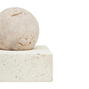 A square-shaped sculpture made of travertine limestone with a fibrous texture, displayed on a white square base.