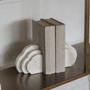 A pair of white marble bookends with a cloud-inspired shape 